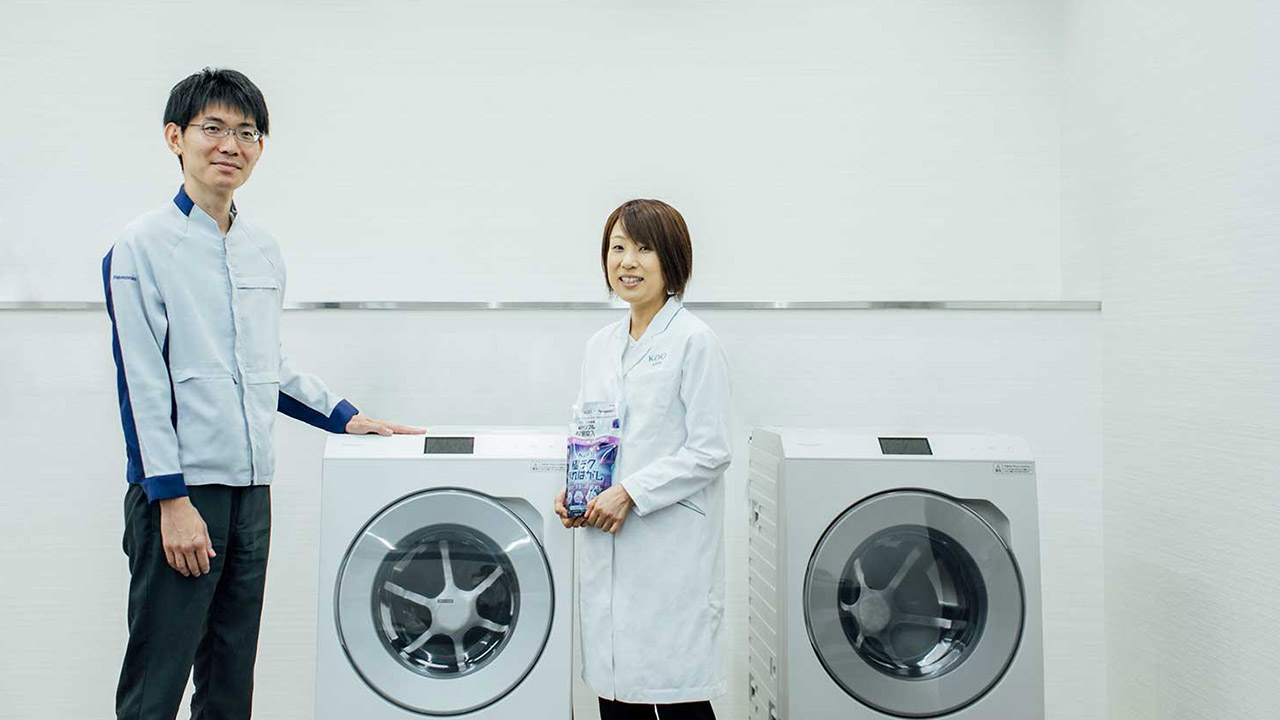 ドラム式洗濯乾燥機の前に立つ喜多亜矢子さんと工藤慶之の写真