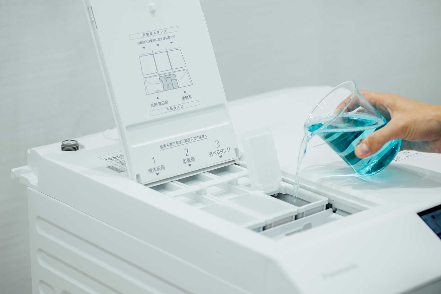 洗濯機の「選べるタンク」に『極ラク汚れはがし』を投入する様子の写真