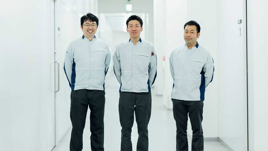 笑顔で立つ作業着姿の3人の男性の写真