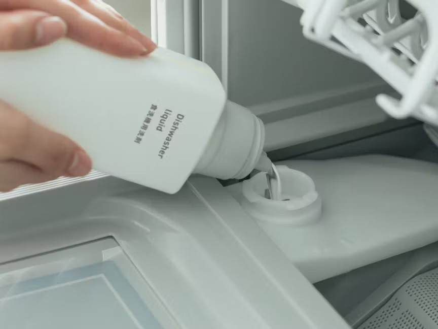 食洗機の投入口に液体専用洗剤を注ぐ手元の写真
