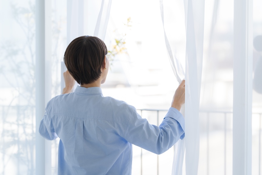 カーテンを開けている女性の写真