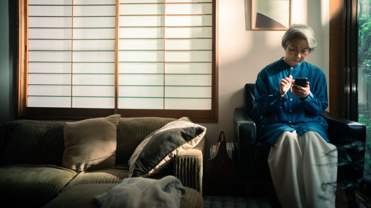 椅子に座ってスマートフォンを操作している女性の写真