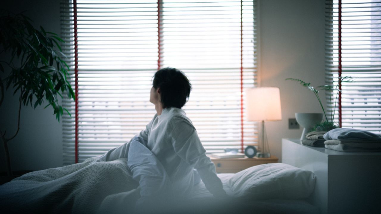 ベッドに座って外を見ている人の写真