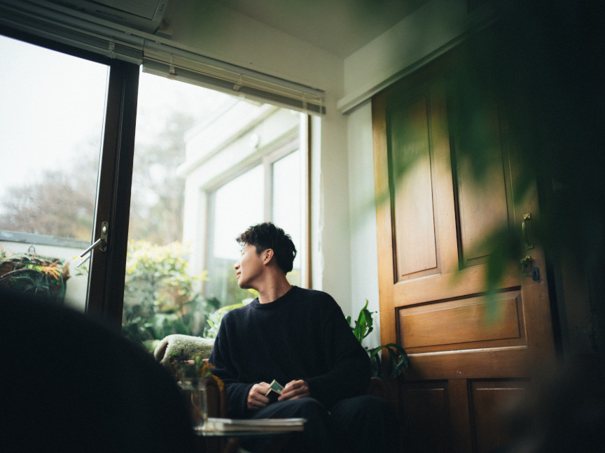 室内で窓の外を眺める人物が椅子に座っている様子。