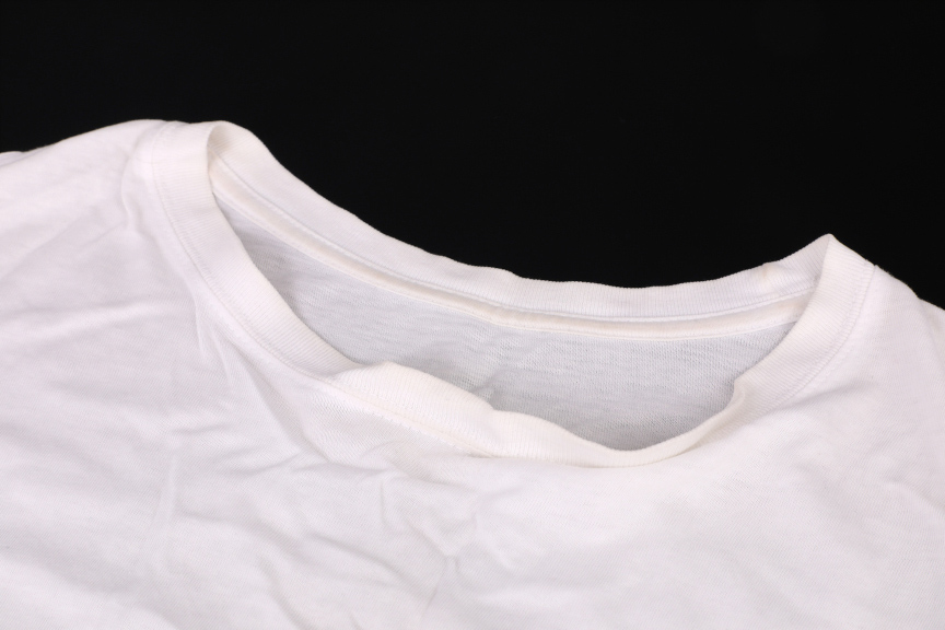白いTシャツの首元部分が平置きで写っている。