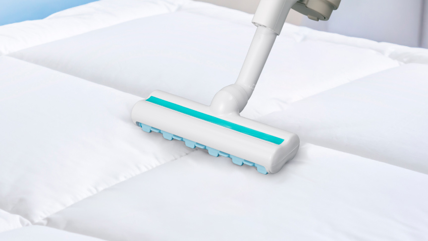 写真：ふとんに掃除機をかけるイメージ