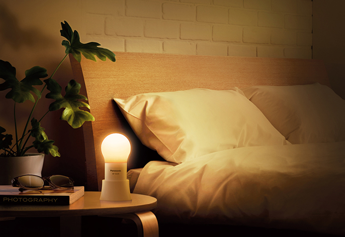 写真:「球ランタン」の利用イメージ。ベッドの近くのサイドテーブルに置いて点灯させている様子。