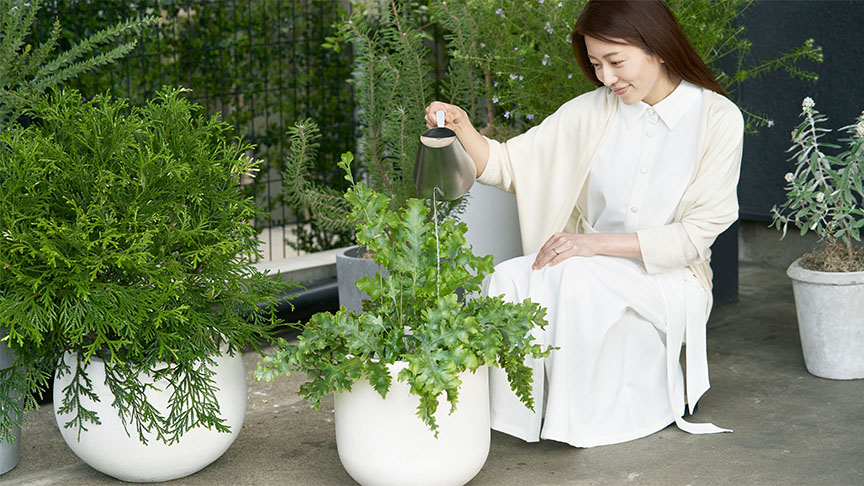 植木鉢に水やりをしている女性の写真