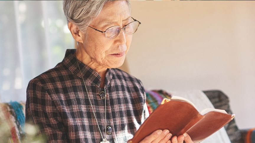 本を読んでいる高齢女性の写真