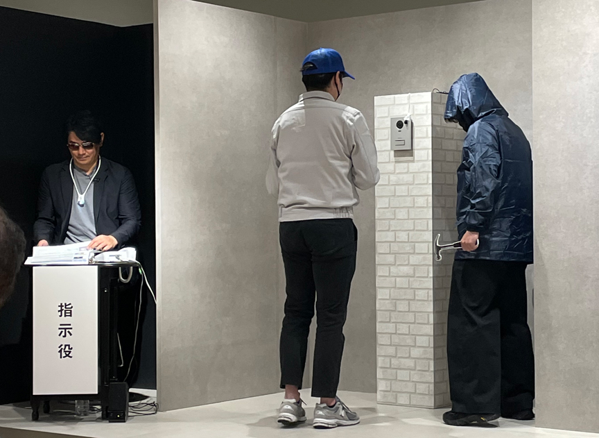 指示役の佐々木さんと闇バイトが侵入強盗の手口を実演している様子の写真