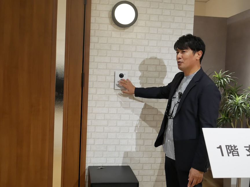 玄関のドアホン機能を実演する佐々木さんの写真