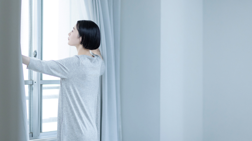 写真：カーテンを開ける女性