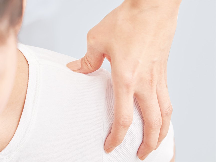 写真：左肩を手で押して、マッサージしている様子