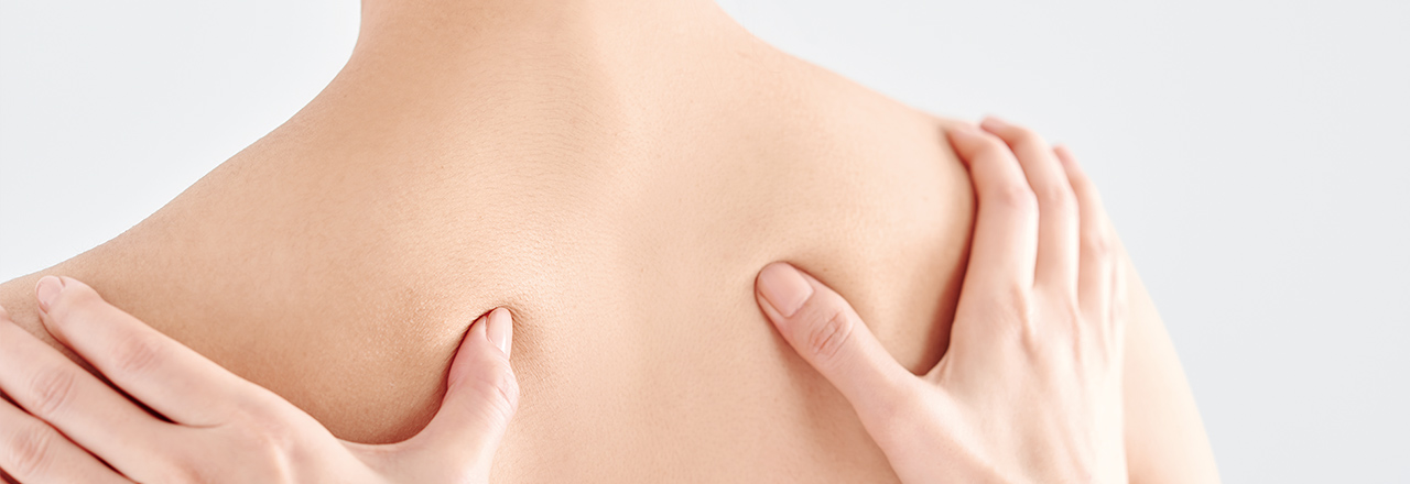 写真：肩甲骨を手で押して、マッサージしている様子