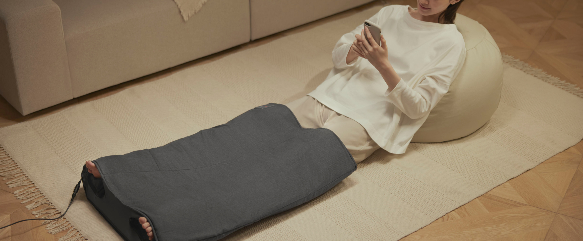 写真：エアマッサージャー はくだけキュッとリフレを使用しながらスマホを操作している女性の様子