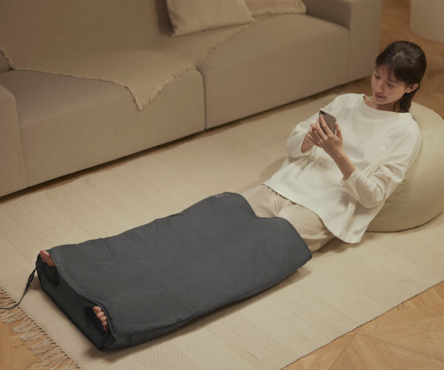 写真：エアマッサージャー はくだけキュッとリフレを使用しながらスマホを操作している女性の様子