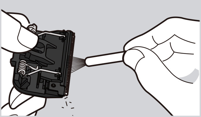イメージ図：掃除用レバーを押さえながら刃の間の毛クズを払い落とす。