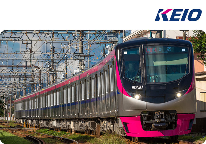 京王電鉄の新型車両5000系が線路を走っている画像です。画像の右上には京王電鉄のロゴがあります。
