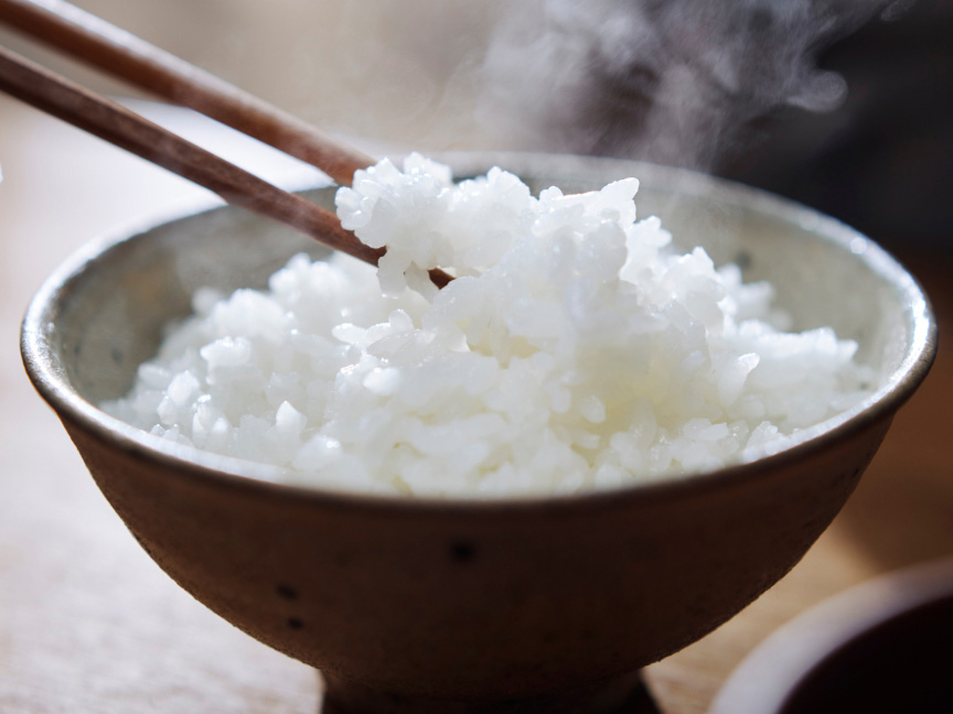 写真：湯気の立つ白ご飯を箸で持ち上げた様子