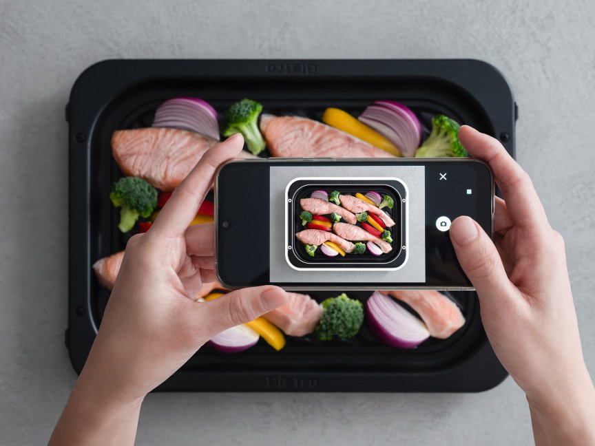 ヒートグリル皿の上に乗せた食材を、スマートフォンで撮影している様子です。