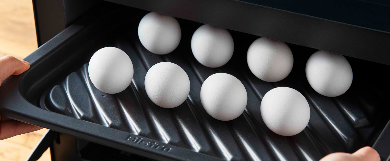 画像：殻付きの卵を載せたヒートグリル皿を庫内に入れる様子