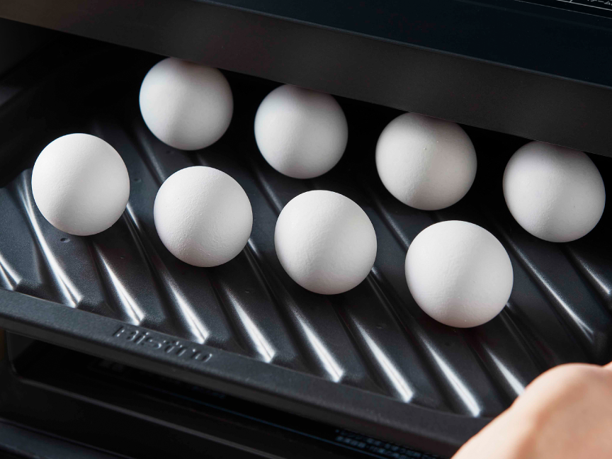 画像：殻付きの卵を載せたヒートグリル皿を庫内に入れる様子