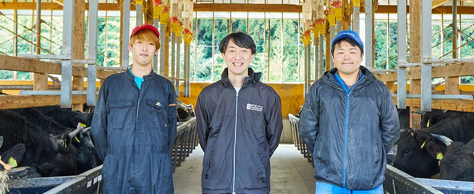 写真：牛舎と大吉牧場の方々