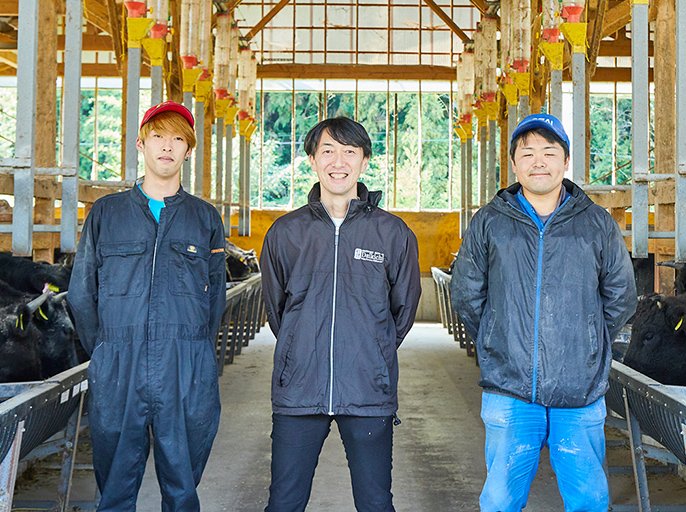 写真：牛舎と大吉牧場の方々