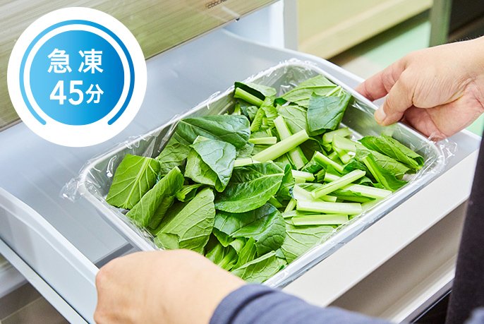 写真：小松菜をバットに入れ、冷凍庫に入れている様子