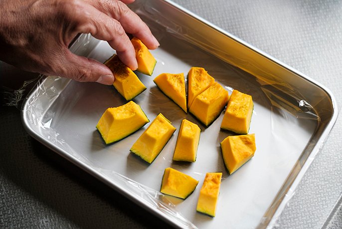 写真：一口大に切ったカボチャをバットに並べる様子