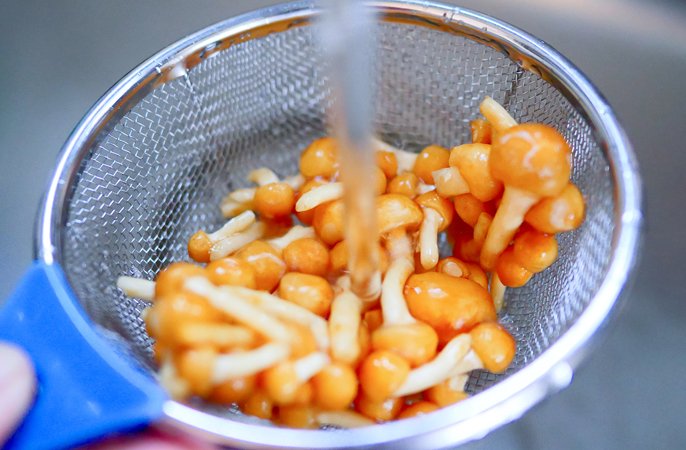 写真：凍ったなめこを流水で洗っているイメージ