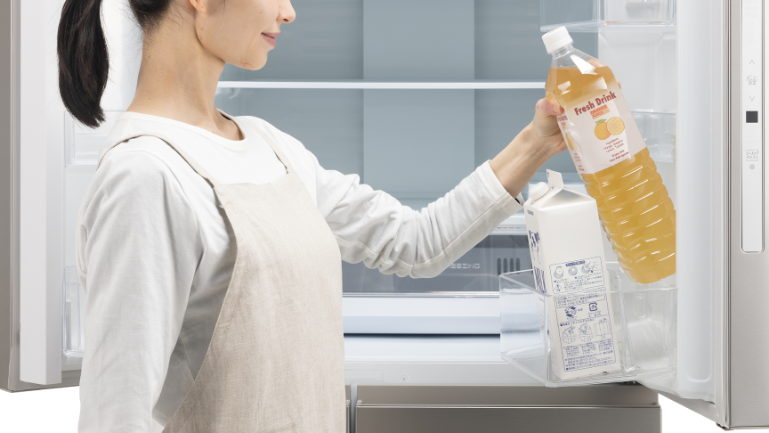 女性が冷蔵室のドアポケットからペットボトルを取り出している写真です。