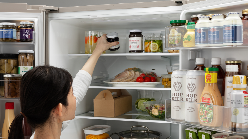 女性が冷蔵室最上段のから食材を取ろうとしている写真です。