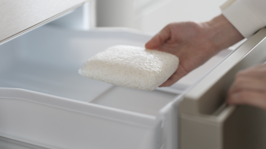 画像：クーリングアシストルームにラップで包んだごはんを入れている女性