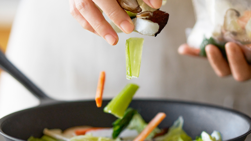 写真：野菜をパラパラとフライパンへ入れるイメージ