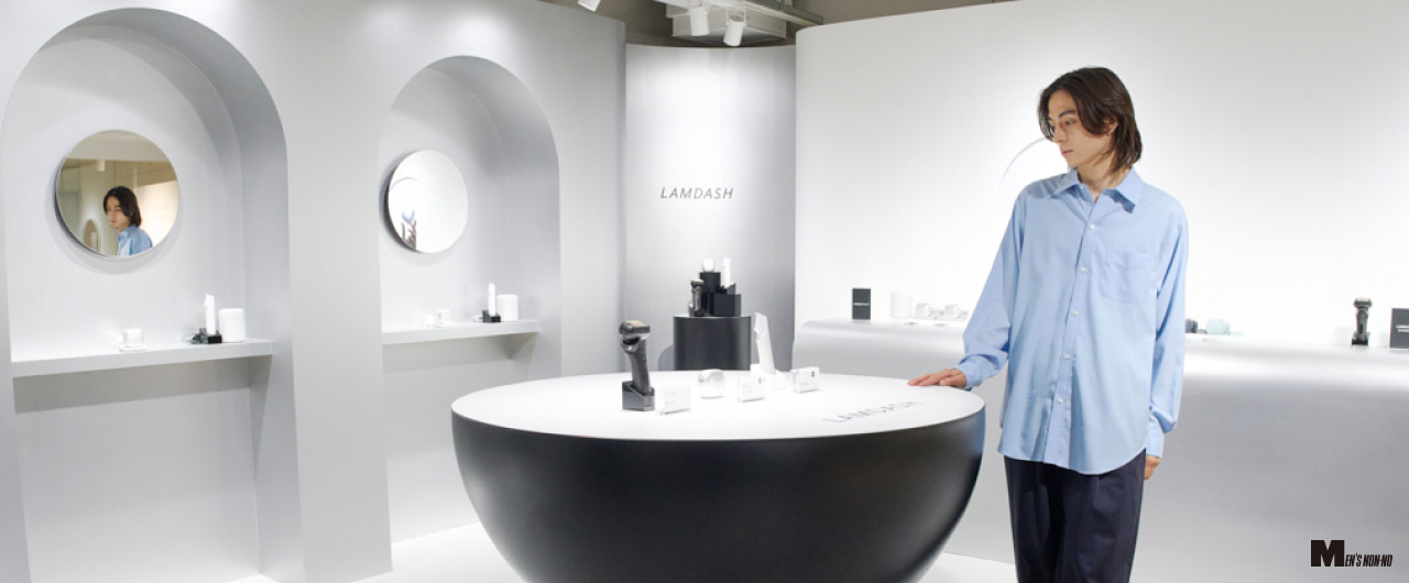 写真：ラムダッシュ特設ルームで、松岡光さんが展示テーブルを見ている様子  MEN'S NON-NO