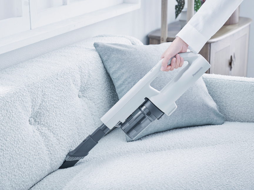 写真：ソファのすき間を掃除する様子