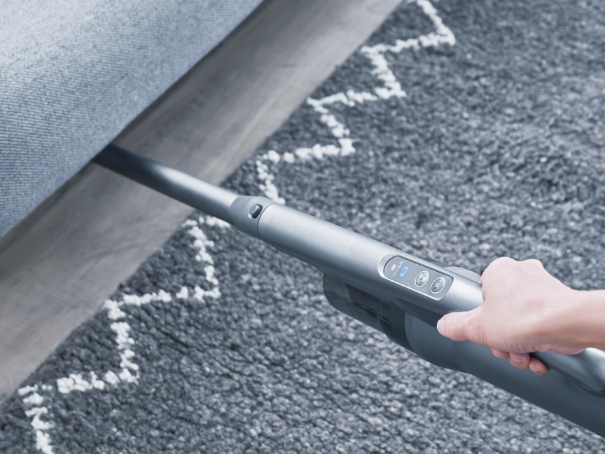 写真：家具下を掃除し手元のランプ表示で確認する様子