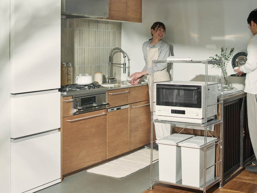 CV:白い家電を置いたキッチンで作業する2人（冷蔵庫・電子レンジ・炊飯器）