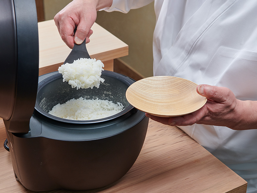 神田さんがVシリーズで炊いたごはんを皿によそっている画像です。