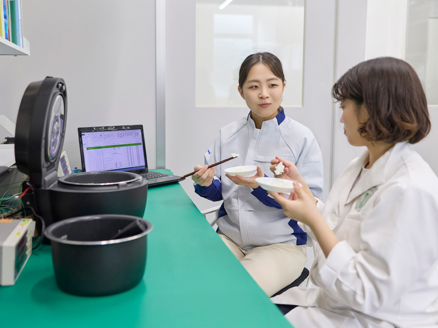 写真：お米を試食しながら炊飯器とパソコンに向かう森川さんと萩さん