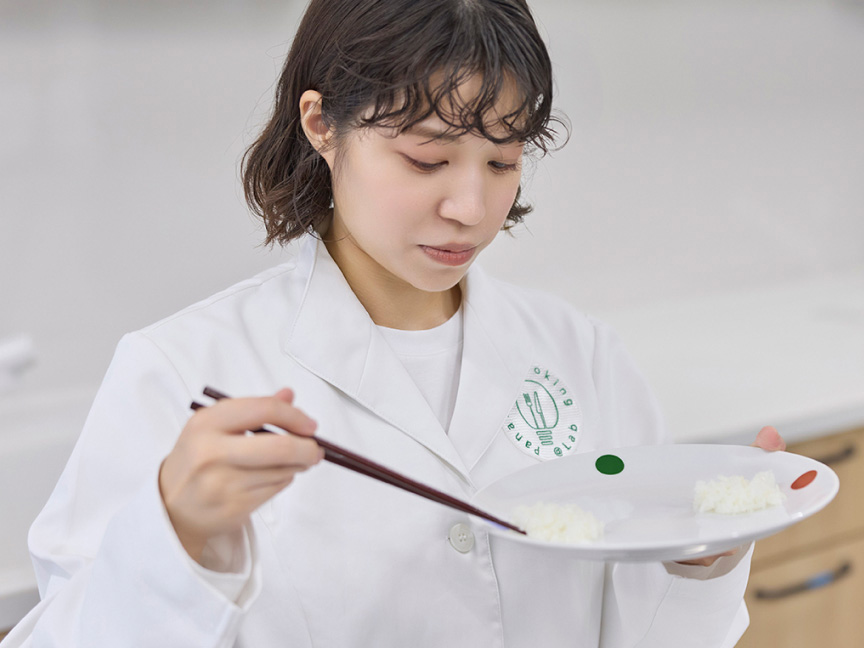 写真：皿にのせられた白米を箸でつまむようす