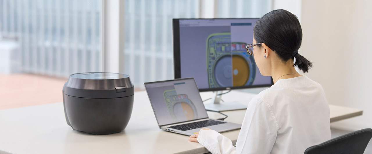 写真：炊飯器とパソコンに向かう吉備さん