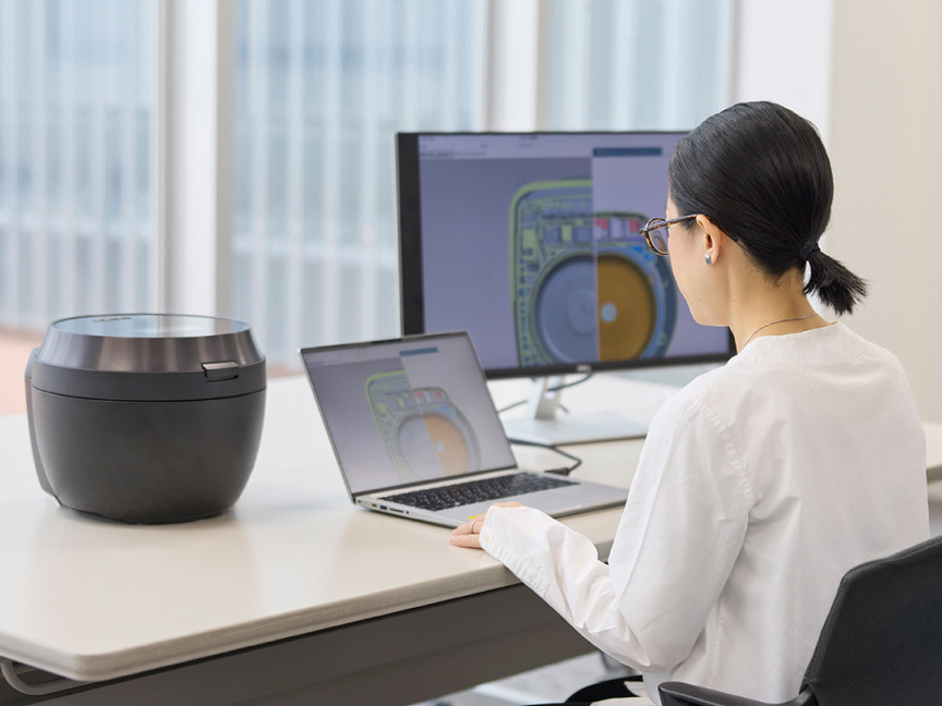 写真：炊飯器とパソコンに向かう吉備さん