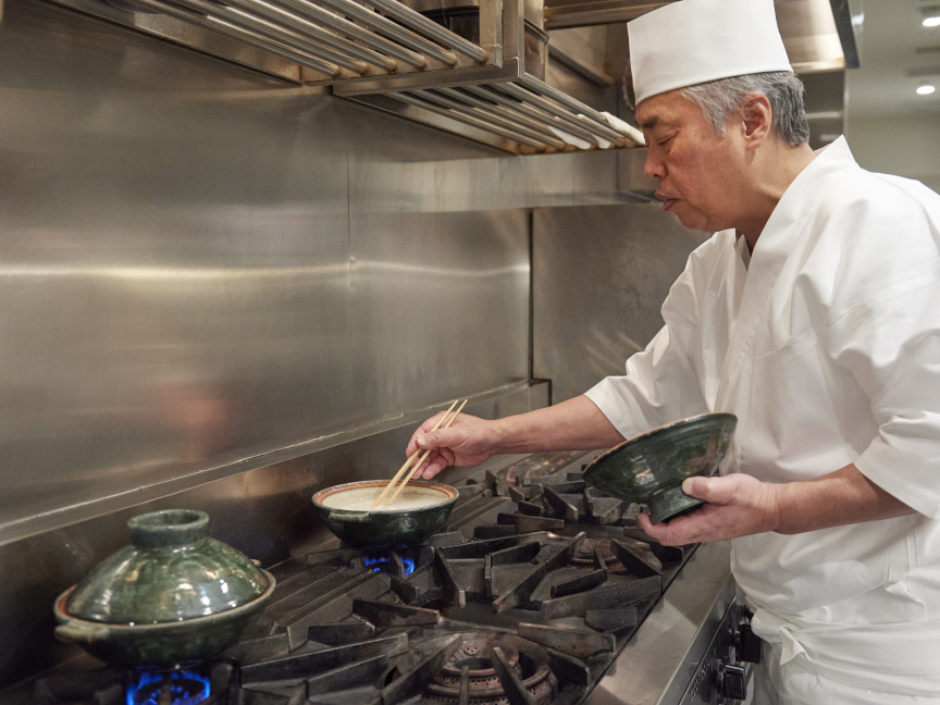 神田さんが土鍋の中のお米の浮き加減を触って確認している画像です。
