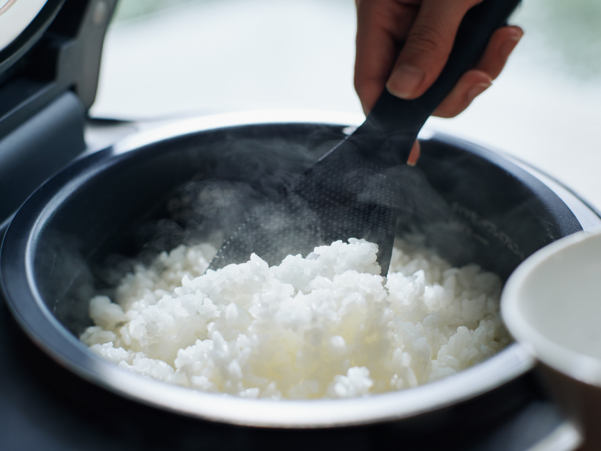 炊飯器から茶碗にごはんをよそっている画像です。