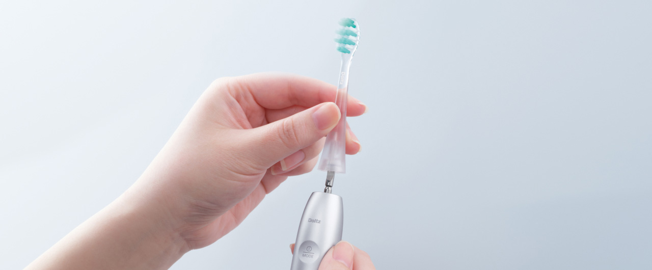 写真：ドルツプレミアムW音波振動ハブラシの透明ブラシを取り外している様子