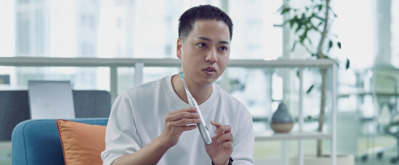 写真：山村有史さんがドルツプレミアムW音波振動ハブラシを手に持っている様子