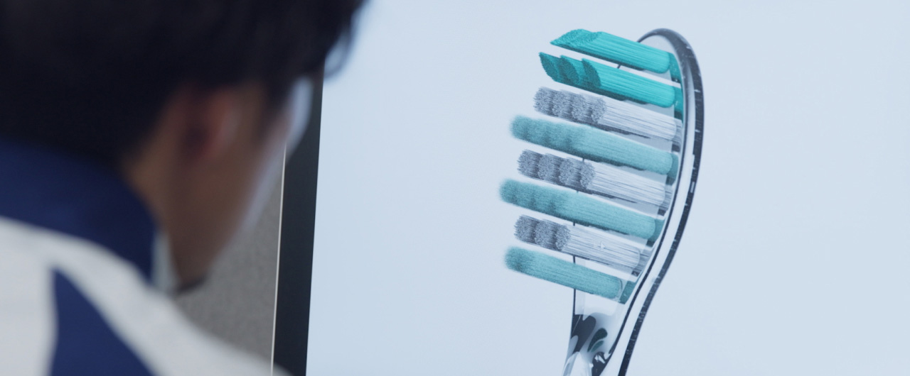 写真：歯間フィットブラシが映ったモニター画面をみている様子