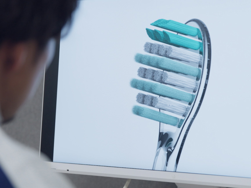 写真：歯間フィットブラシが映ったモニター画面をみている様子